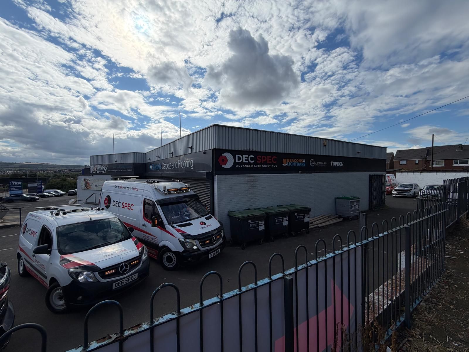 Two white Dec-Spec vans parked outside the unit